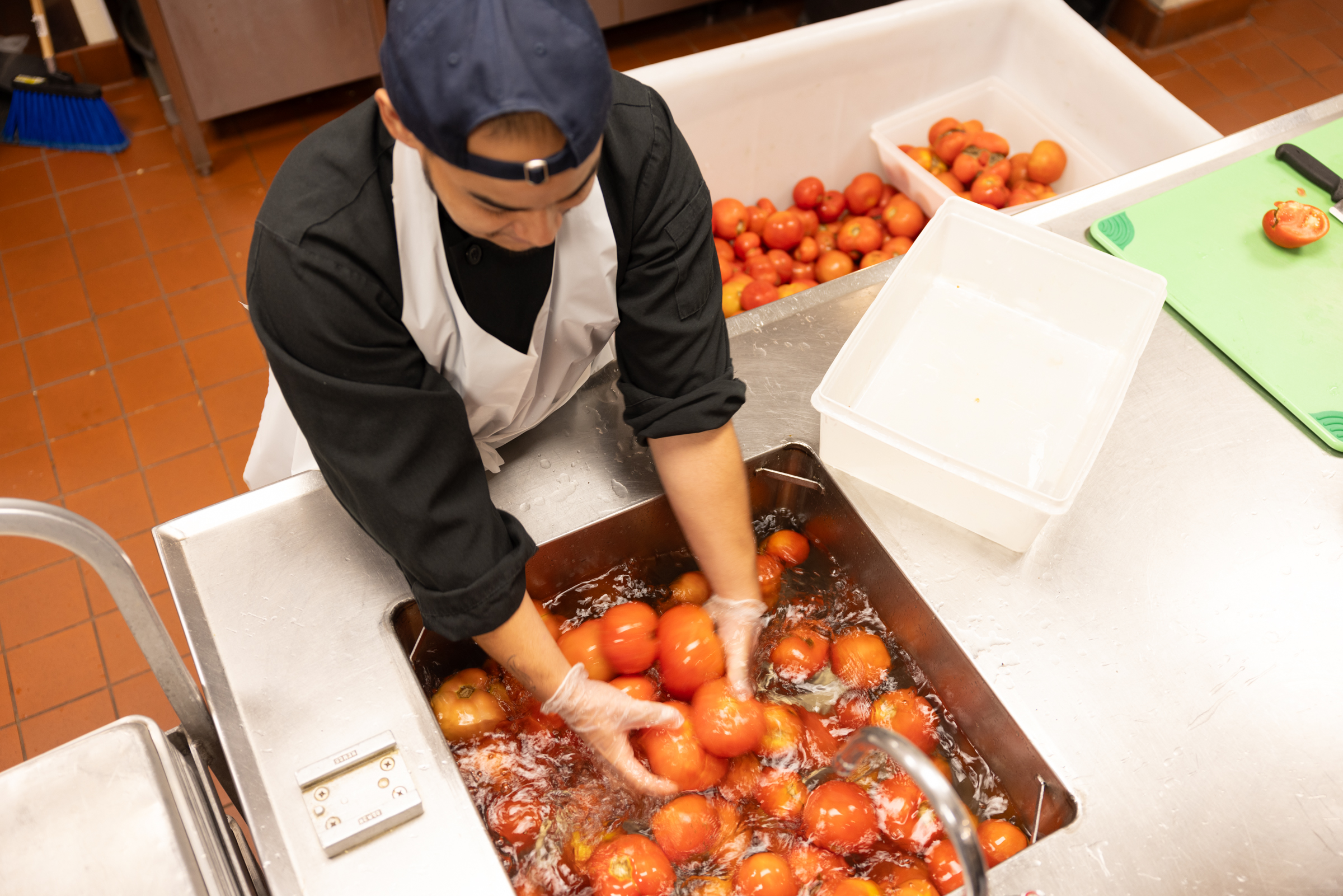 Teaching Kitchen trainee washing tomatoes